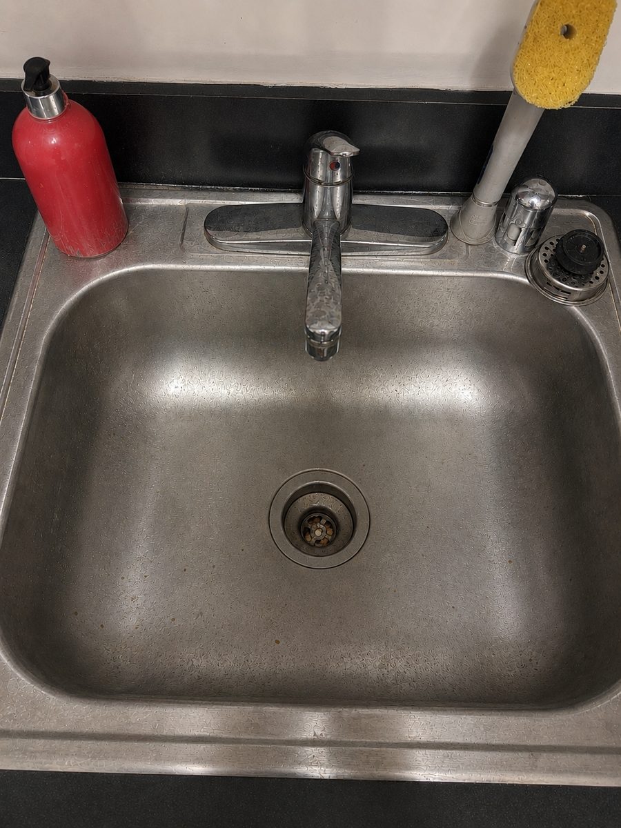 Kitchen sink before Ivybrook cleaning, with a dull, grimy drain